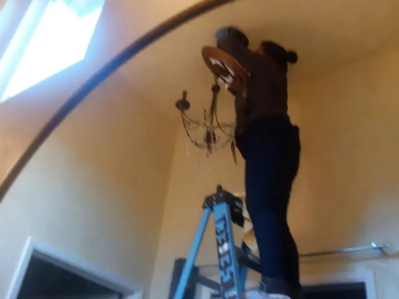 Electrician installing a chandelier in a Sharonville residence